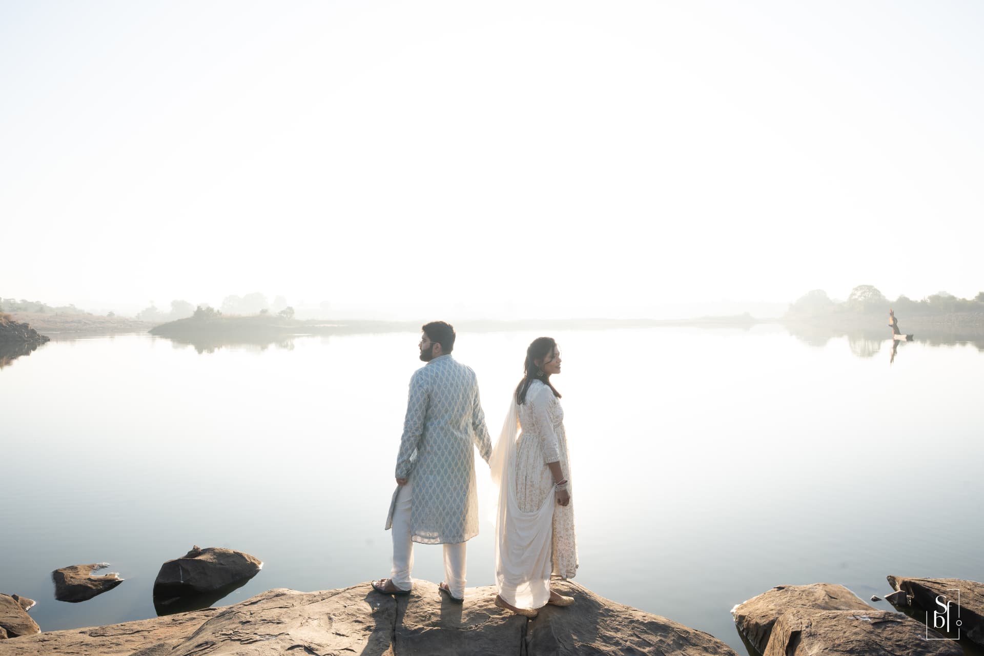 The couple holding hands beside the lake